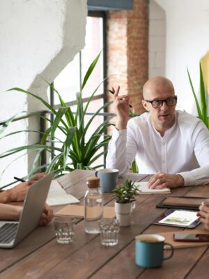 A group of colleagues in a modern office having a strategic discussion around a wooden table.