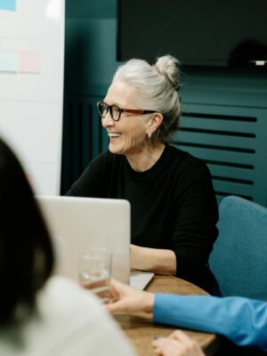 Smiling senior businesswoman leading a diverse team meeting in an office.