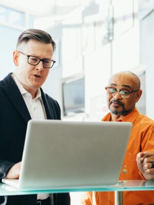 Two business professionals engaged in a collaborative discussion over a laptop in a modern office setting.